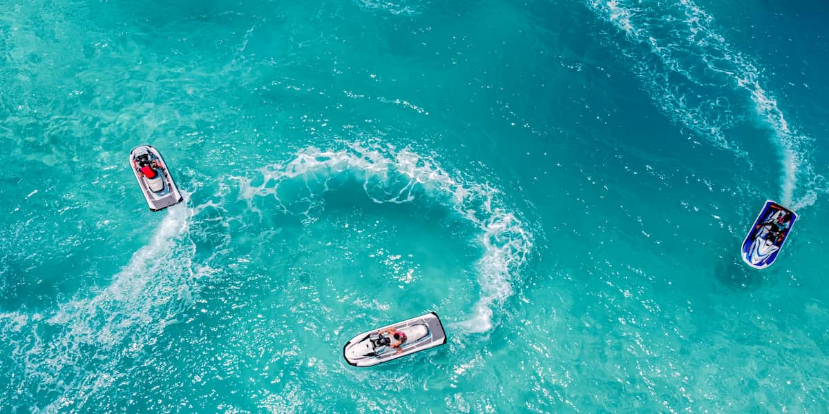 Overhead view of three jet skis creating circular patterns in the crystal-clear waters of Florida, showcasing the importance of understanding Florida jet ski laws for safe and responsible riding.