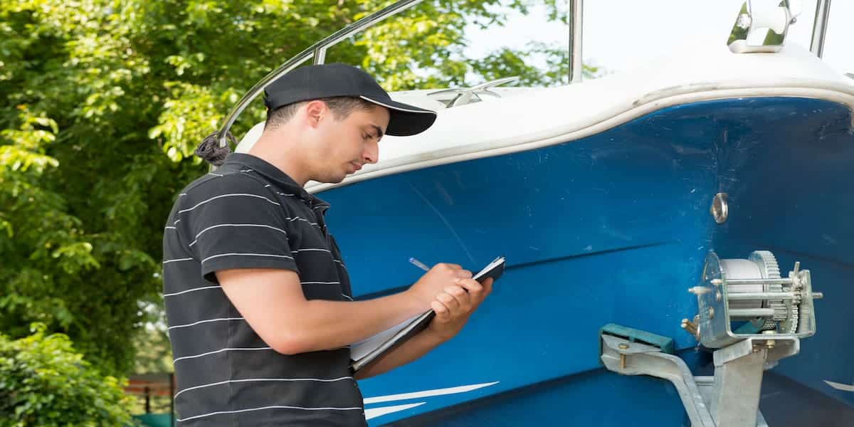 A man inspecting a boat and taking notes, illustrating the process of gathering information for a boating accident report.