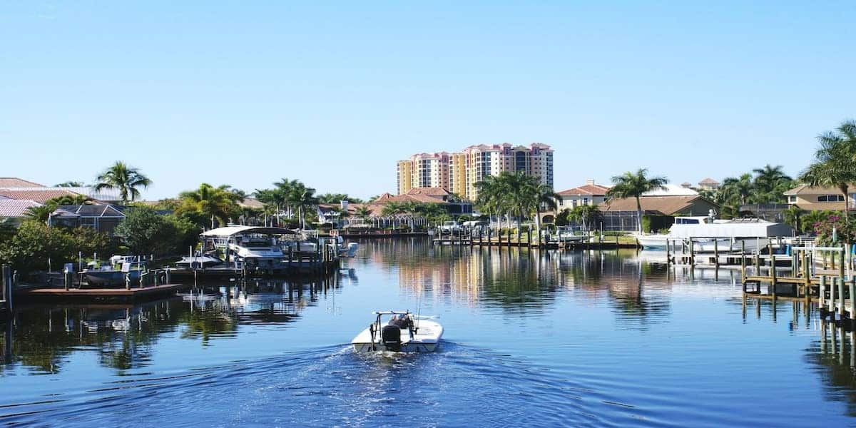 A serene canal lined with boats and palm trees, representing the importance of understanding and filing a boating accident report in waterfront communities