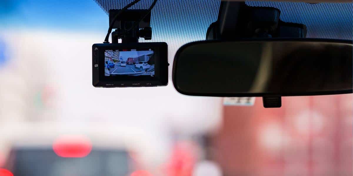 A dash cam is mounted on a car's windshield, recording the road ahead. This image raises the question, do dashcams record when the car is off?