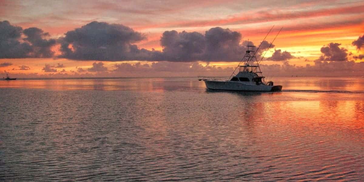 A motorboat gliding across calm waters during a stunning Florida sunset, emphasizing the need to follow Florida boating laws for safety and environmental protection.