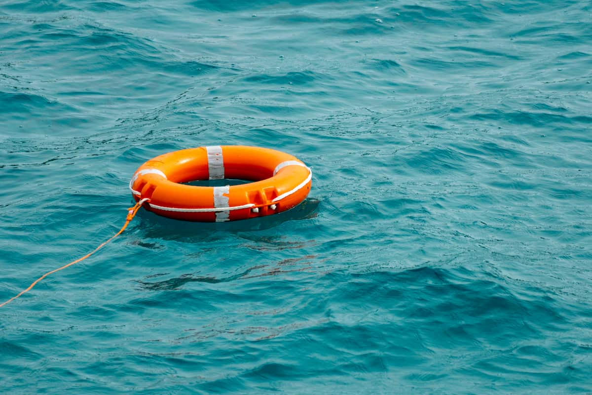 Orange life ring floating in the water, representing what should you always do when a person falls overboard