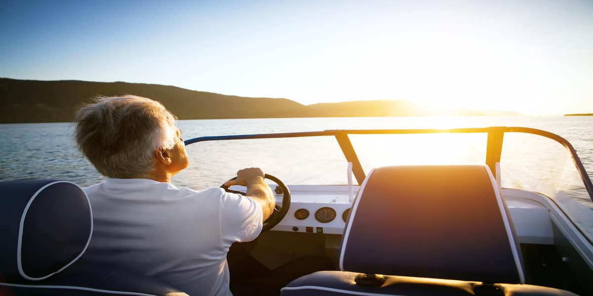 A boat operator steering a motorboat at sunset, symbolizing the importance of knowing what is the first action required of a boat operator who is involved in a boating accident? to ensure safety and compliance with legal responsibilities.