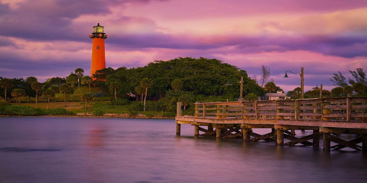 Scenic view of a lighthouse near a wooden pier at sunset, highlighting safety and preparedness for boat operators who need to understand what is the first action required of a boat operator who is involved in a boating accident.