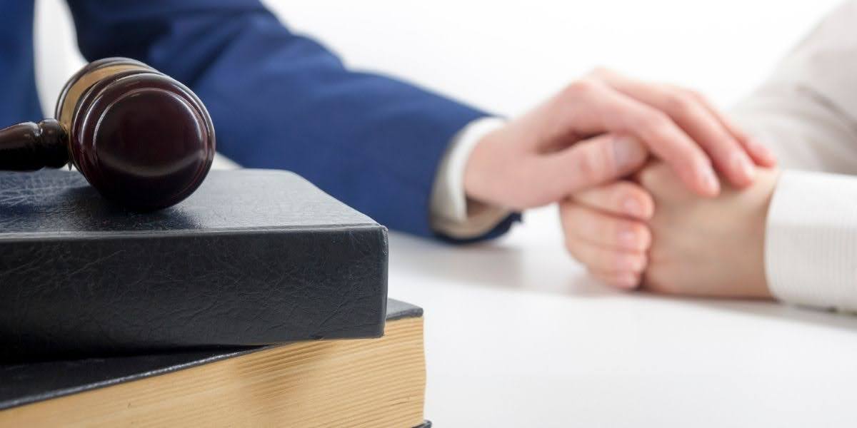 A judge’s gavel resting on legal books with two individuals holding hands, symbolizing legal support and justice in wrongful death examples cases.